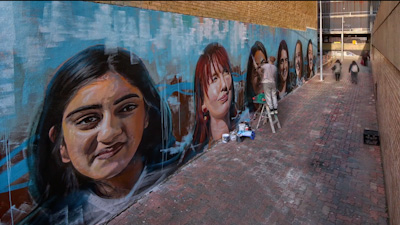 Artist painting a large Sydney laneway mural celebrating Indian culture
