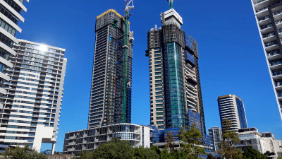 Two large towers under construction surrounded by several completed large high-rises towers.